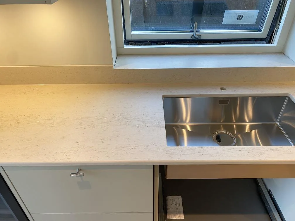 Närbild av matt Dekton Danae köksbänkskiva med underlimmad rostfri diskho och stänkkant vid fönster i Lerum.