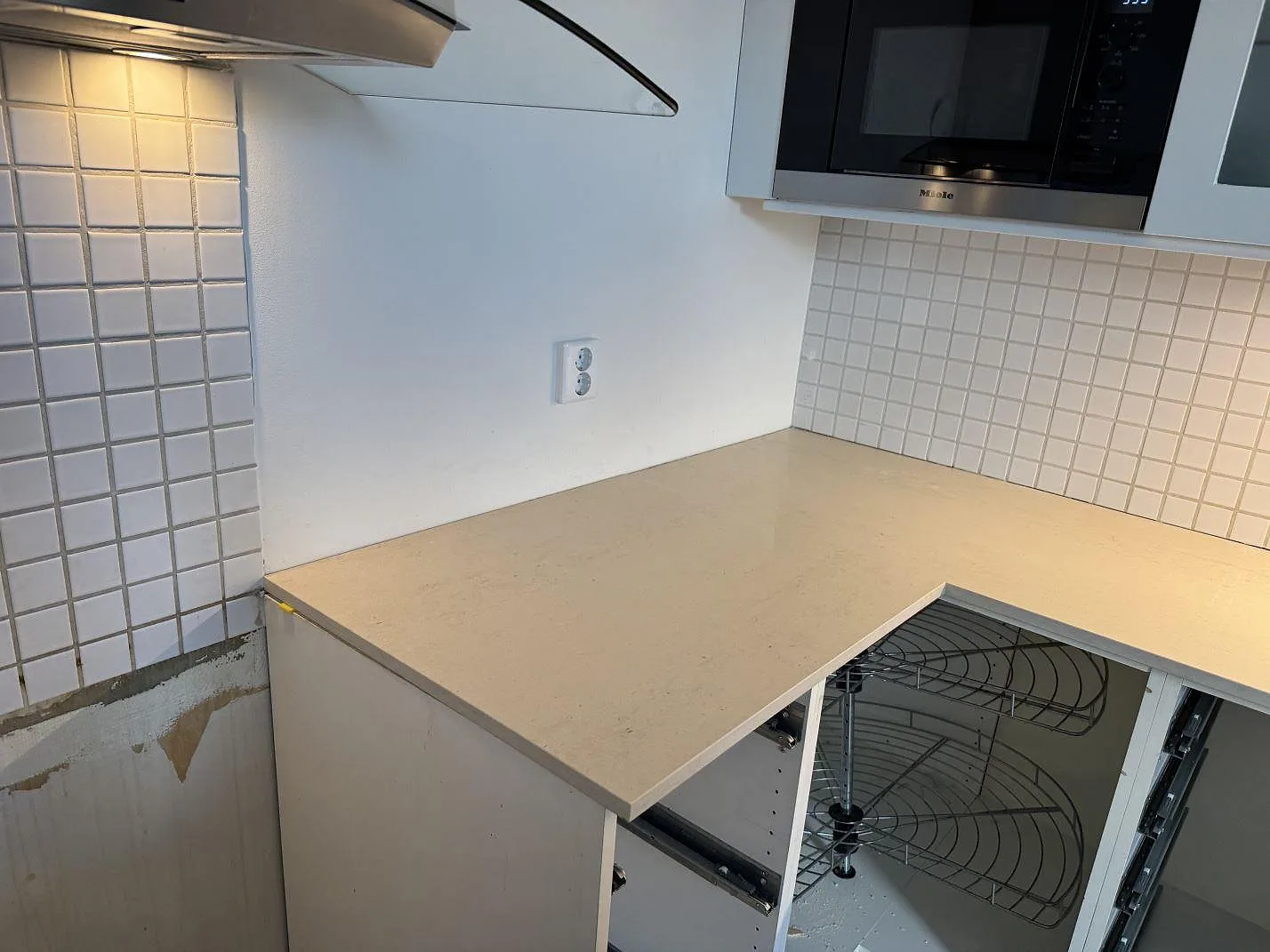 L-formad köksbänkskiva i matt Dekton Danae med ljus keramikyta under väggskåp i Limhamn.