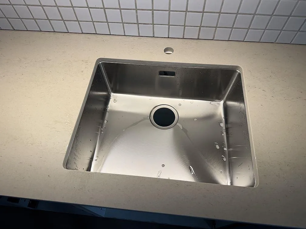 Närbild på matt Dekton Danae runt diskhon, ljus keramisk bänkskiva med diskret teckning i Limhamn.