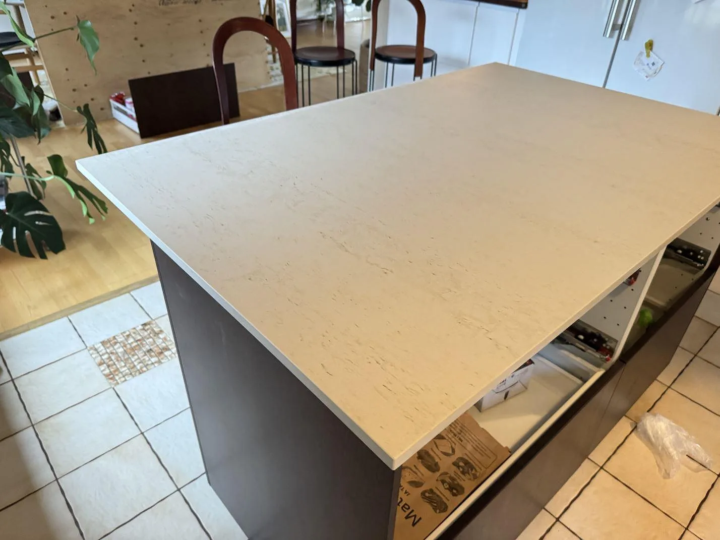 Närbild av monterad köksö i matt Dekton Danae, ljus keramisk sten med rak kant och öppna köksstommar i Limhamn.