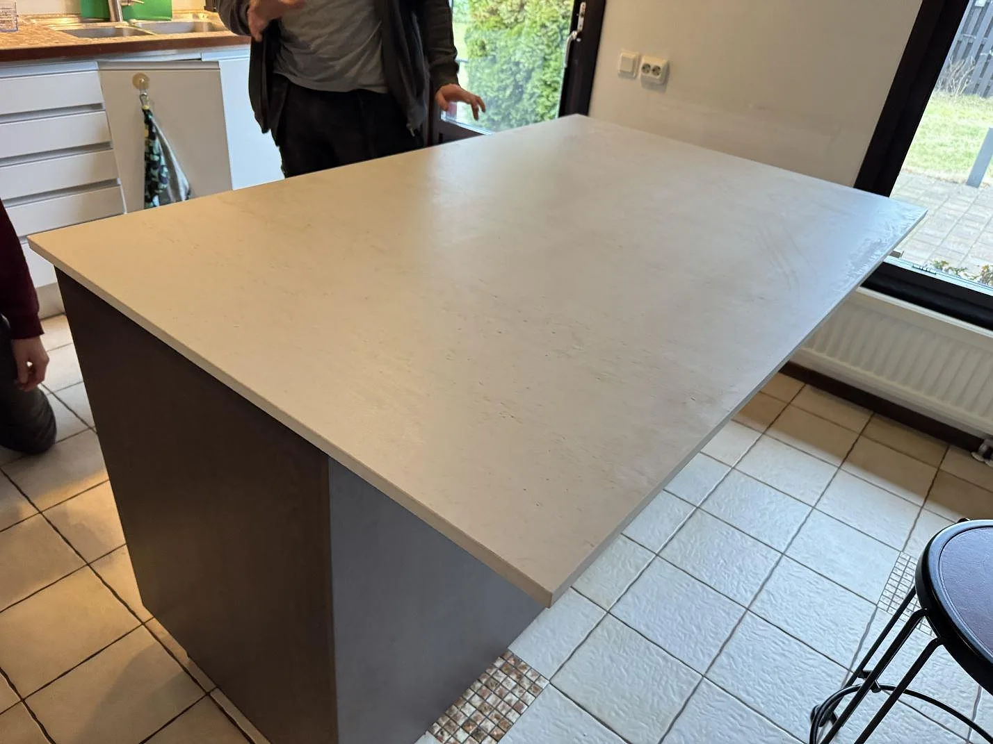 Köksbänkskiva i matt Dekton Danae på köksö, fotograferad under montering med kök och fönster i Limhamn.