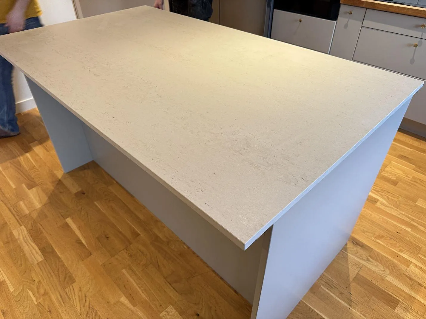 Köksö i Dekton Danae, matt krämig keramik med travertinlik ådring, i ett kök i Limhamn.