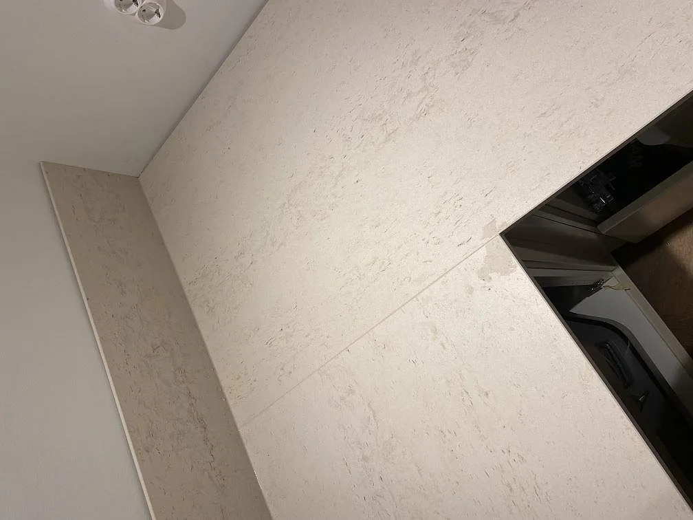 Matt yta och låg stänkkant i Dekton Danae köksbänkskiva, varm taupeton, i ett kök i Lomma.