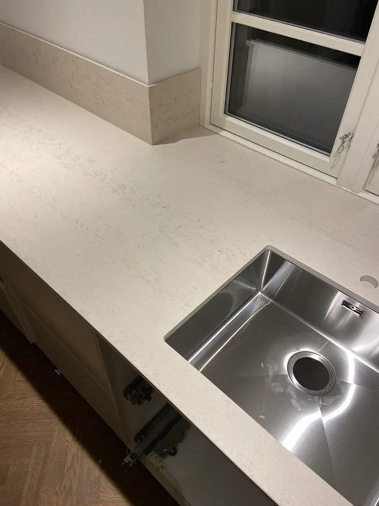 Underlimmad rostfri diskho i köksbänkskiva av Dekton Danae, matt yta, i ett kök i Lomma.