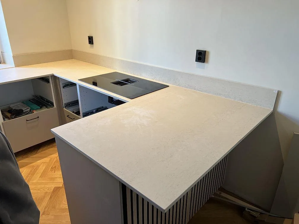 Köksbänkskiva i matt Dekton Danae, ljus keramik, med svart induktionshäll, låg stänkkant och köksö i Malmö.