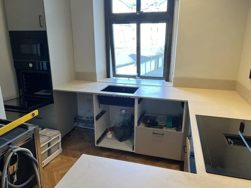 Kök i Malmö med matt Dekton Danae som bänkskiva, låg stänkkant, svart häll och diskhozon vid fönstret.
