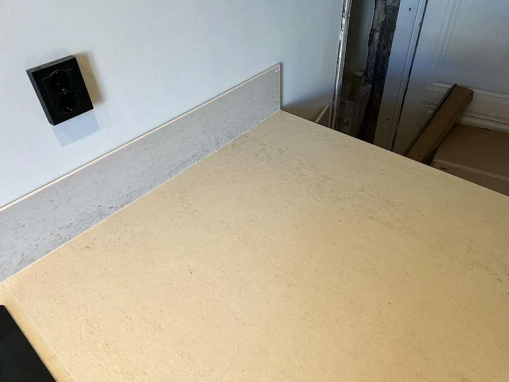 Detalj av matt Dekton Danae som ljus köksbänkskiva med 8 mm stänkskydd och vägguttag i Malmö.