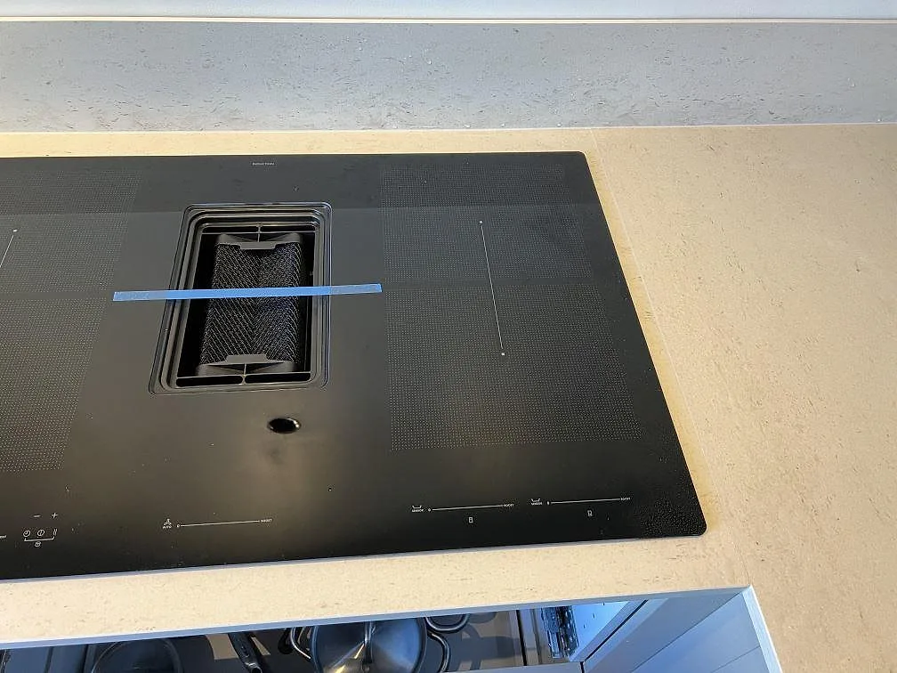 Närbild på svart induktionshäll monterad i matt Dekton Danae med låg stänkkant i ett kök i Malmö.