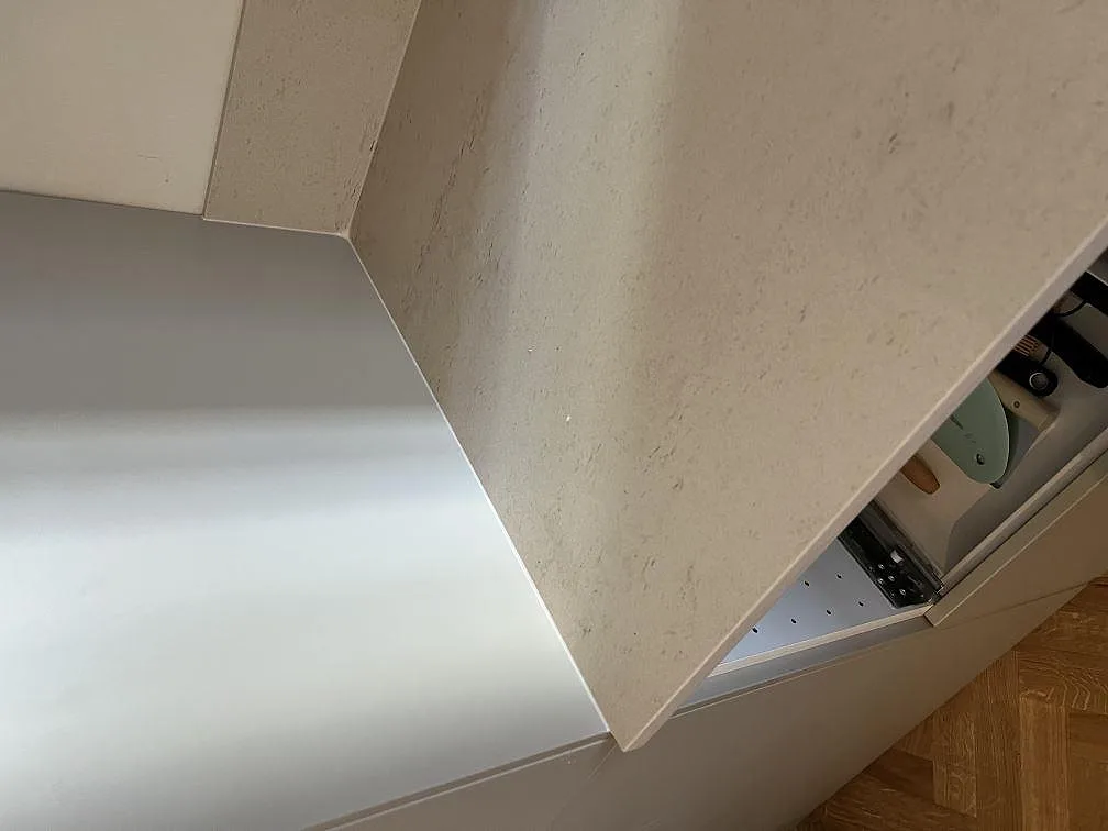 Närbild på hörn och stänkskydd i matt Dekton Danae över ljusa köksstommar och parkettgolv i Malmö.