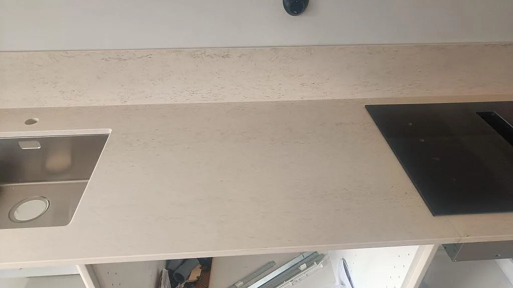 Detalj av matt Dekton Danae bänkskiva mellan rostfri diskho och svart häll i ett kök i Malmö.