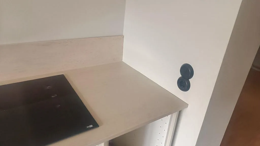 Hörndetalj vid hällen på en ljus matt Dekton Danae bänkskiva monterad på vita köksstommar i Malmö.