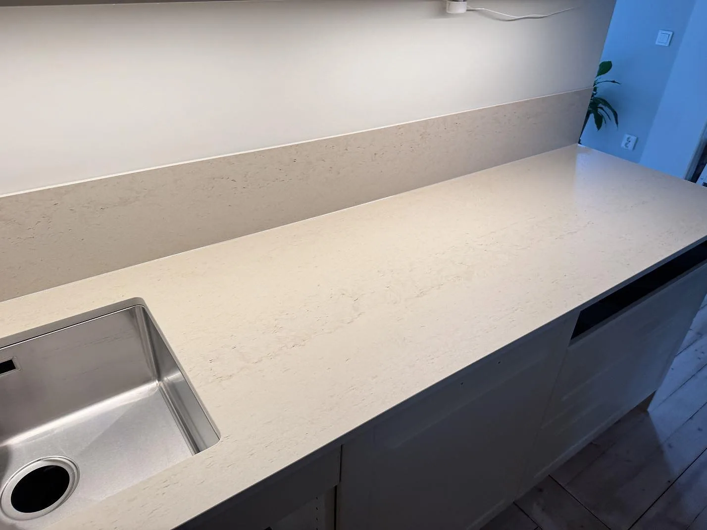 Köksbänkskiva i matt Dekton Danae keramik med rostfri diskho och matchande stänkskydd i ett kök i Malmö.