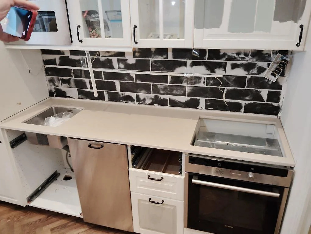 Köksbänkskiva i matt Dekton Danae, 20 mm keramik, med ljus yta, diskhoöppning och svart tegelliknande stänkyta i Stockholm.