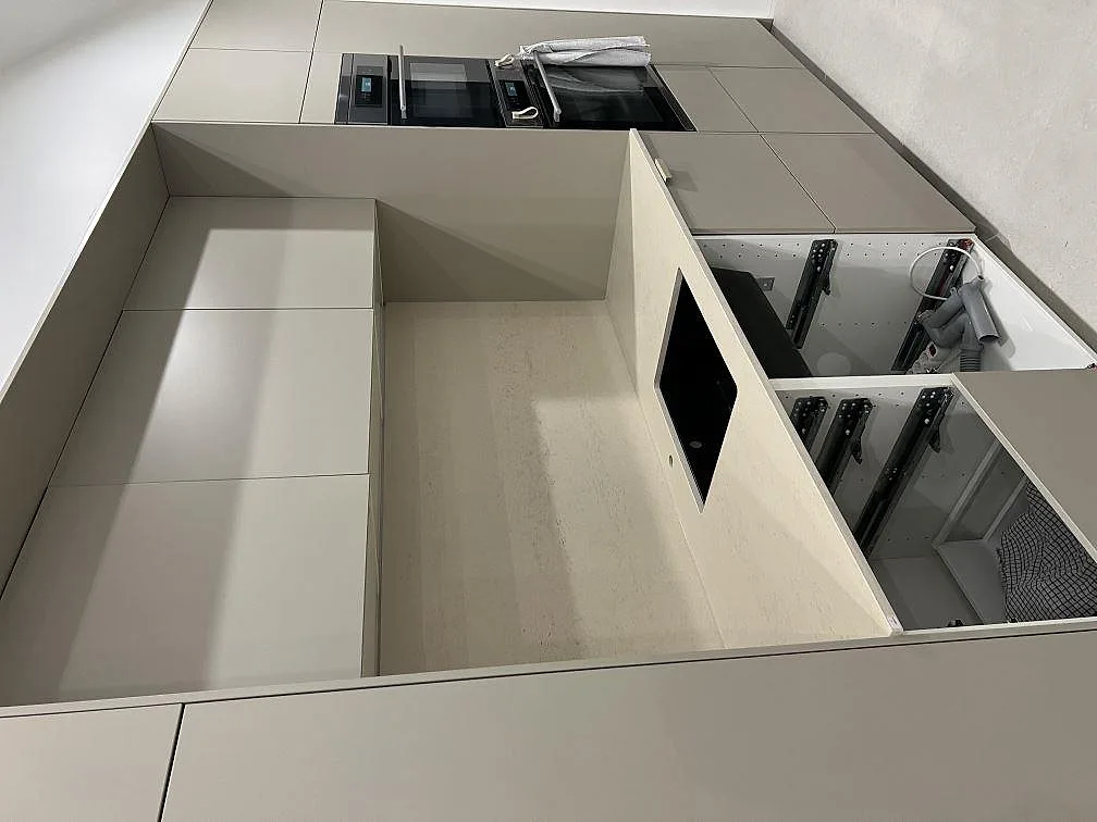 Detalj av köksbänkskiva i matt Dekton Danae, beige keramik, med sidopanel och öppna köksstommar under montering i Stockholm.