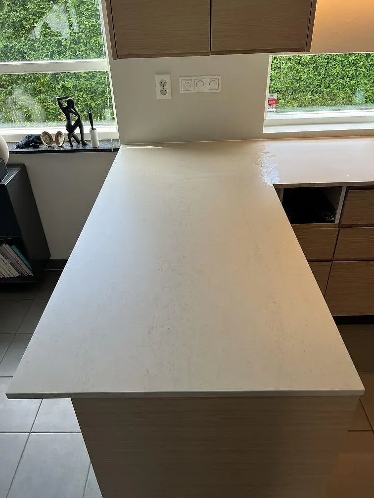 Halvö i ljus matt Dekton Danae med diskret ådring och träinredning i ett kök i Trelleborg.