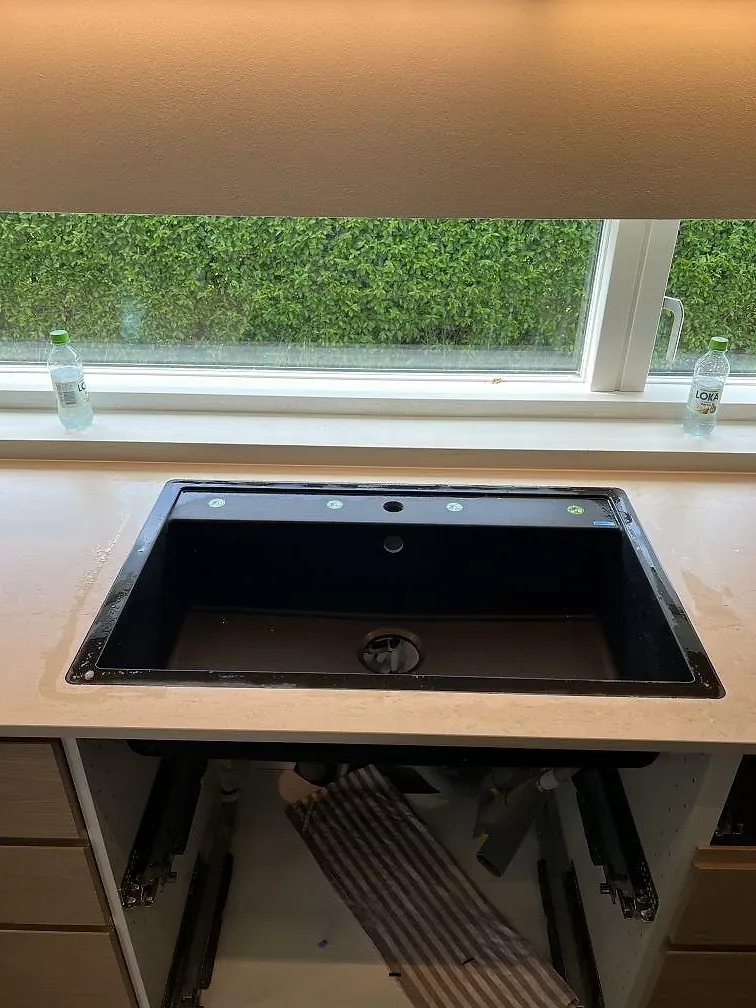 Underlimmad svart diskho i matt Dekton Danae vid ett fönster mot trädgården i Trelleborg.