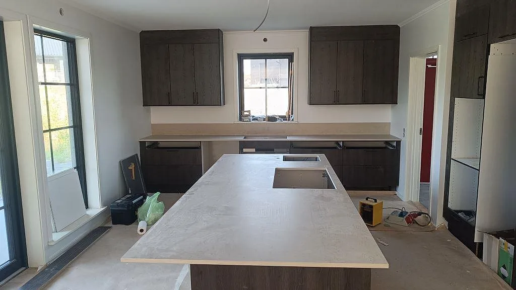 Köksbänkskiva i matt Dekton Danae keramik med köksö, öppningar och lågt stänkskydd i ett kök i Uddevalla.