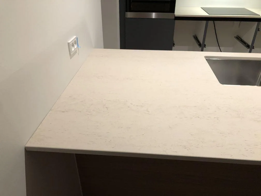 Köksbänkskiva i varmvit Dekton Danae, matt, på köksö med underlimmad rostfri diskho i ett kök under montering i Værløse.