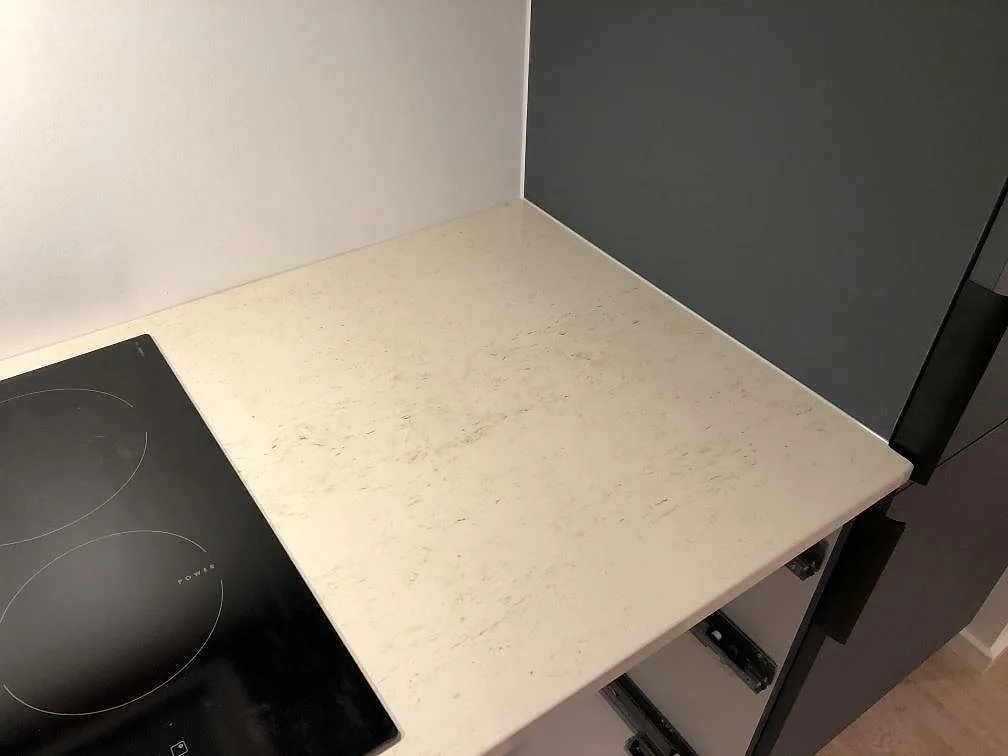 Bänkskiva i varmvit Dekton Danae med induktionshäll i hörnet av ett kök under montering i Værløse.