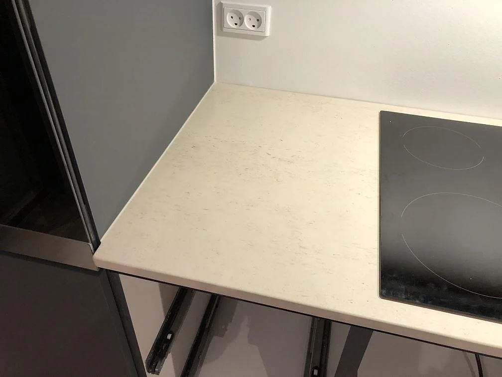 Köksbänkskiva i Dekton Danae med infälld induktionshäll och uppvikt stänkkant mot väggen i ett kök i Værløse.