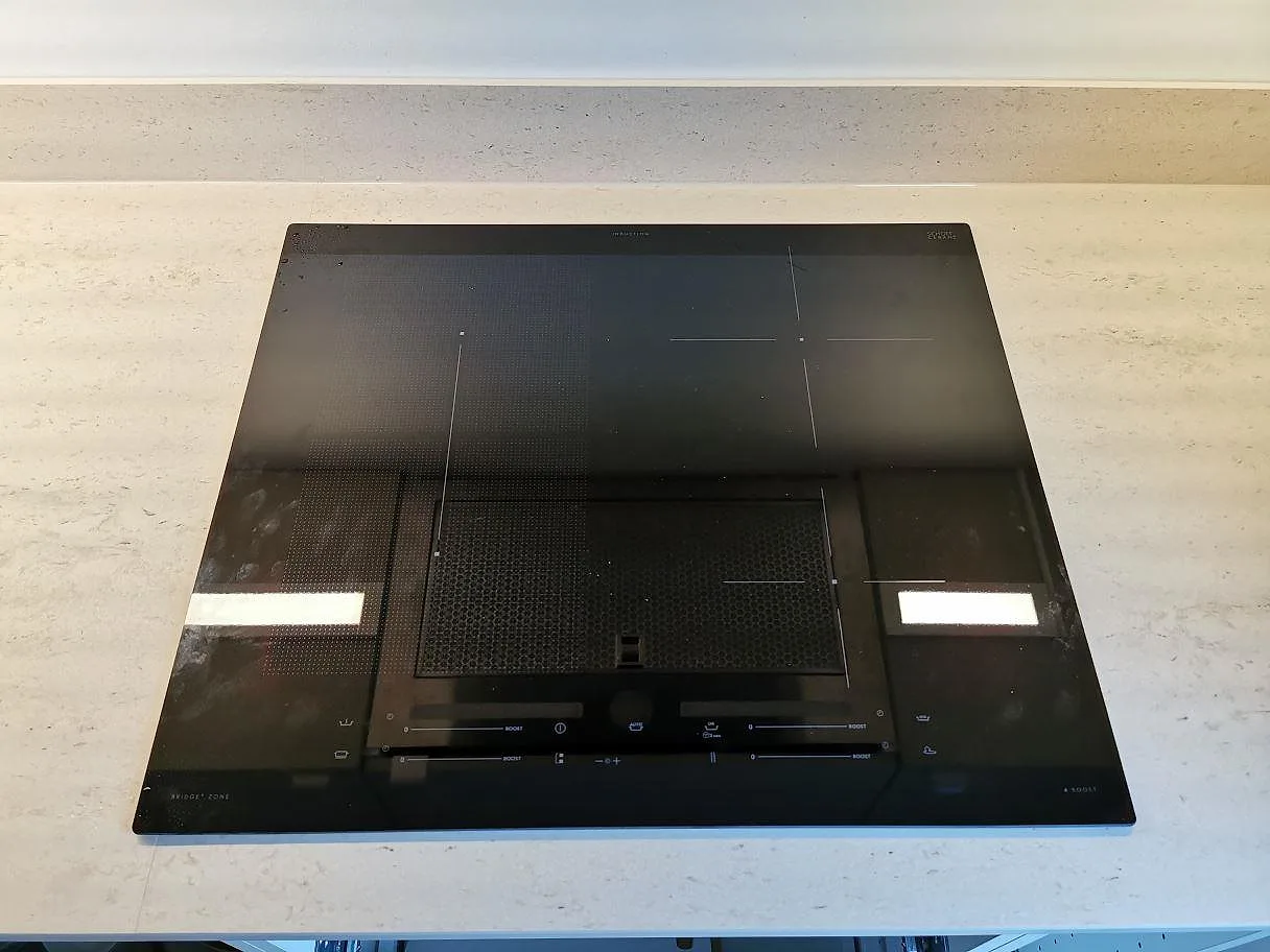 Övermonterad induktionshäll i en köksbänkskiva i Dekton Danae sedd ovanifrån, matt yta, i ett kök i Vellinge.