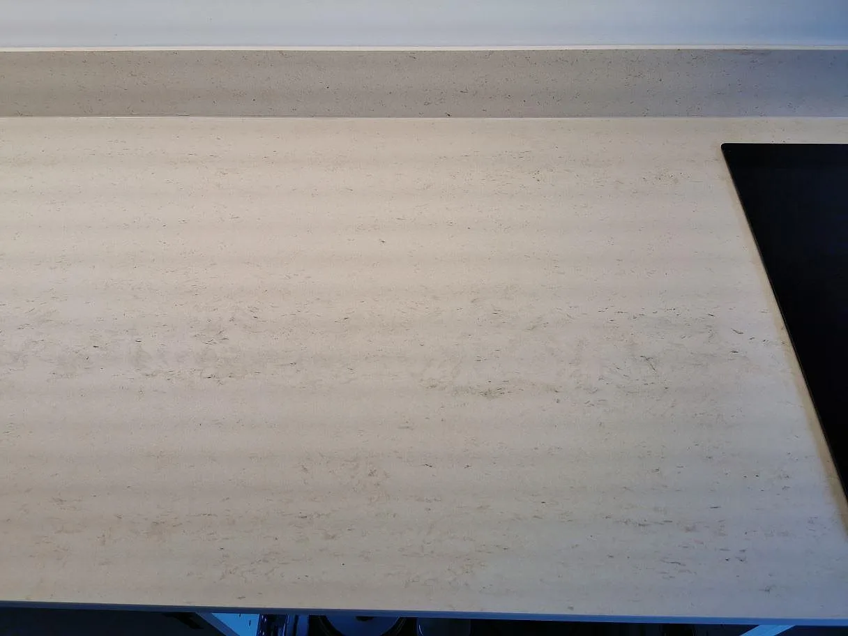 Köksbänkskiva i Dekton Danae med uppvikt stänkskydd och induktionshäll, matt greige yta, i ett kök i Vellinge.