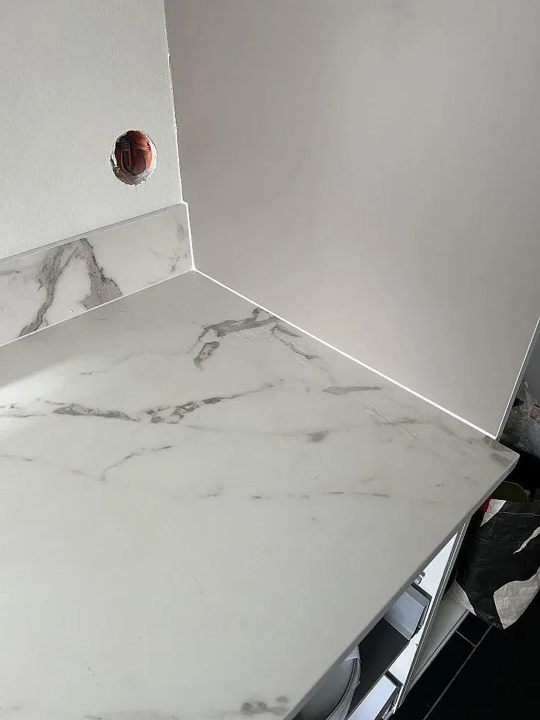 Installerad Dekton Daze KC Velvet bänkskiva med matt yta, grå ådring och väggdetalj under montering i Malmö.