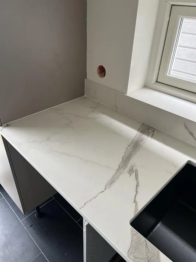 Hörn av köksbänkskiva i Dekton Daze KC Velvet, matt vit keramik med grå ådring och låg stänkkant i Malmö.