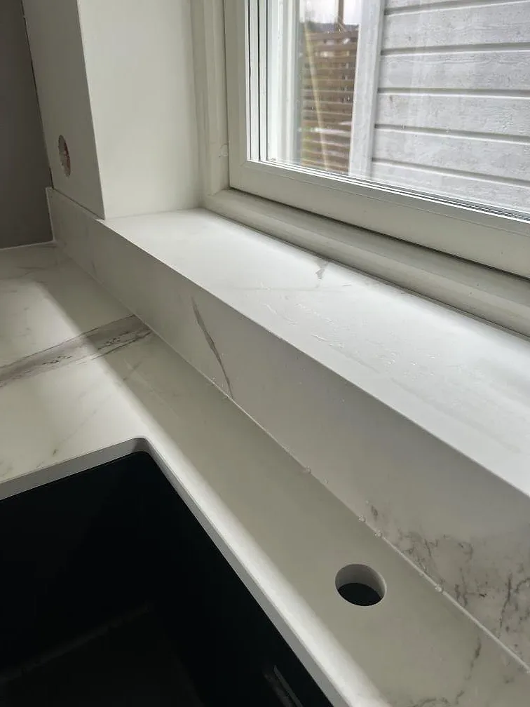 Fönsternisch och låg stänkkant i matt Dekton Daze KC Velvet med ljus marmorlook i Malmö.