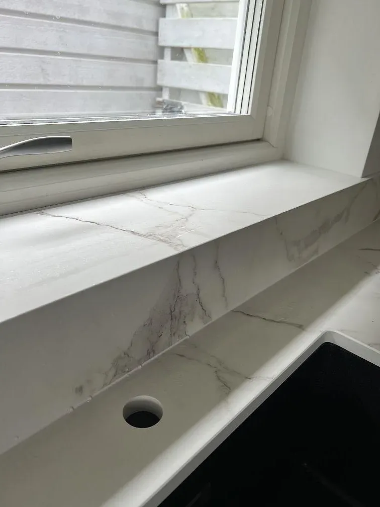 Närbild på fönsterbänk och stänkkant i vit Dekton Daze KC Velvet med grå ådring i Malmö.