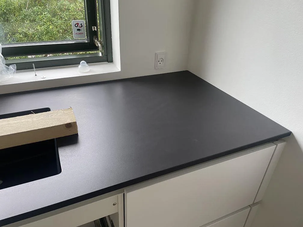 Detalj av matt Dekton Domoos köksbänkskiva vid fönster och underlimmad svart diskho i Greve.