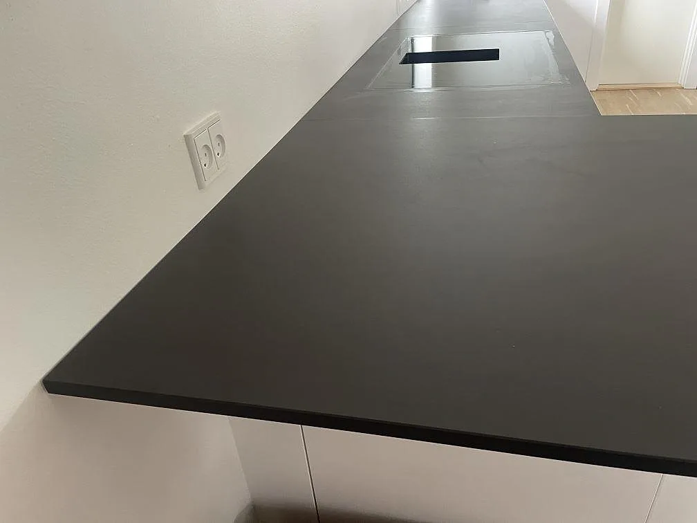 Närbild på mörk matt Dekton Domoos bänkskiva med hällurtag och tunn framkant i ett kök i Greve.