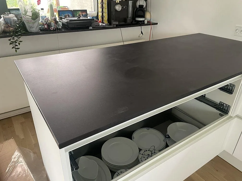 Peninsula i matt Dekton Domoos keramik på vita köksstommar med matchande mörk fönsterbänk i Greve.