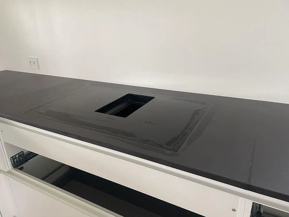 Hällurtag i mörk matt Dekton Domoos köksbänkskiva med skyddsfilm under montering i Greve.