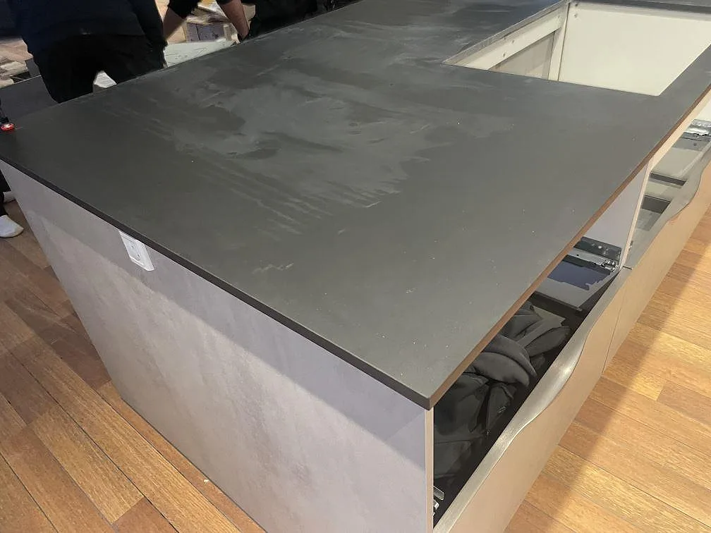 Sidovy av köksö med matt Dekton Domoos, tunn mörk kant och öppna lådstommar under montering i Haslev.