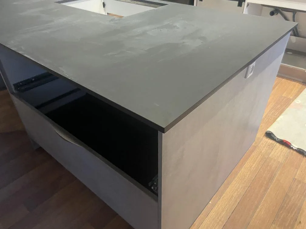 Detalj av köksö i matt Dekton Domoos med mörk keramisk skiva och öppen förvaring i Haslev.