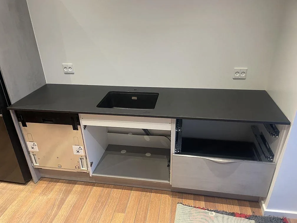 Rak köksbänkskiva i matt Dekton Domoos med svart infälld köksdetalj och öppna köksstommar i Haslev.