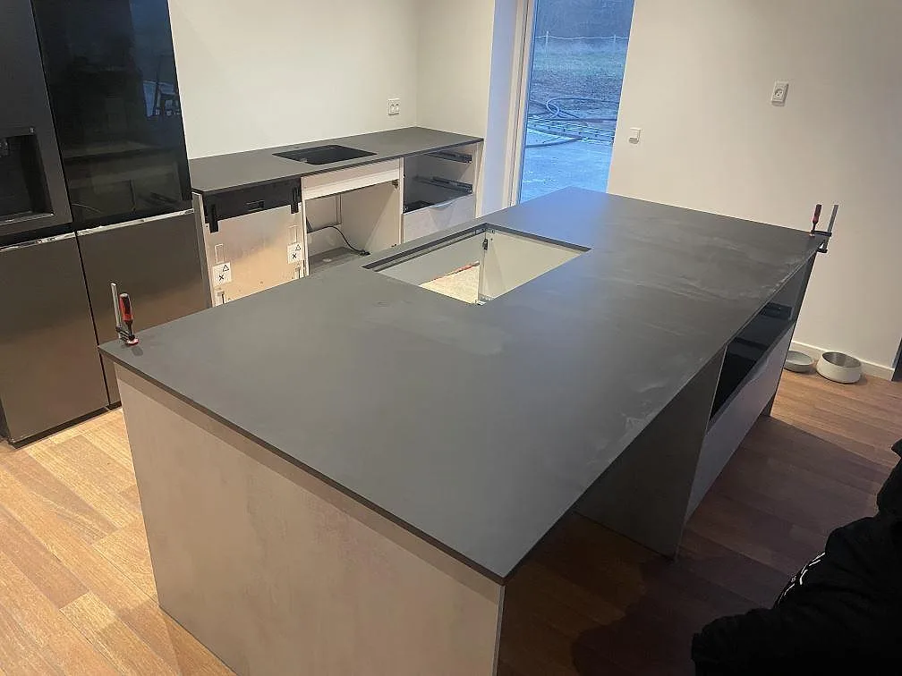 Köksbänkskiva i matt Dekton Domoos med köksö och rak bänkrad under montering i Haslev.