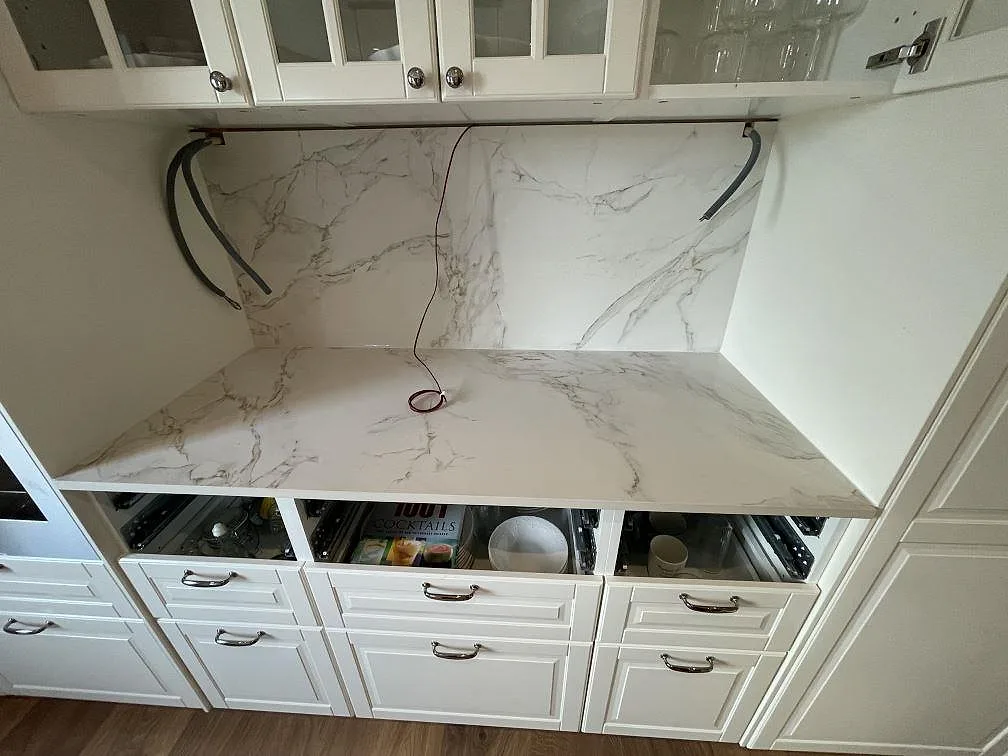 Köksbänkskiva och stänkskydd i vitt Dekton Entzo med grå ådring, matt yta, i ett kök under montering i Borlänge.