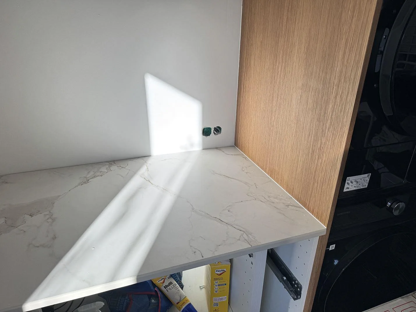 Köksbänkskiva i matt Dekton Entzo med tydlig grå ådring intill en svart inbyggnadsugn i ett kök under montering i Frederikssund.