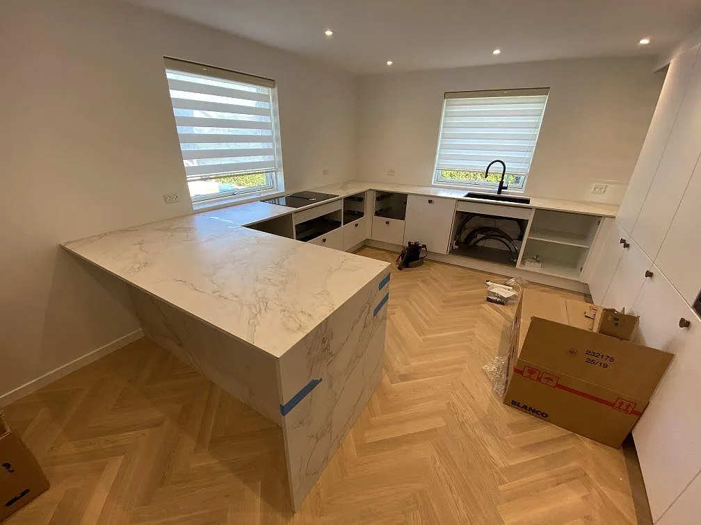 Köksbänkskiva och köksö i matt Dekton Entzo keramik med ljus ådring och låg stänkkant i ett kök i Glostrup.