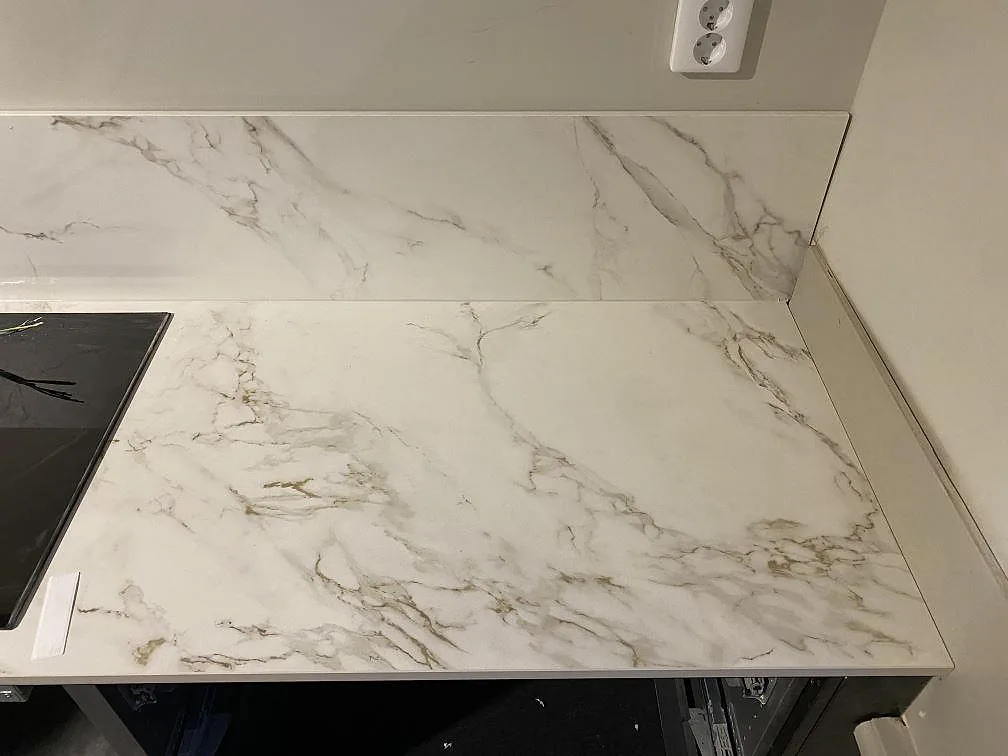 Höger del av köksbänkskiva i matt Dekton Entzo med låg stänkskiva och vägguttag i Göteborg.