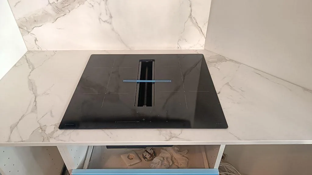 Köksbänkskiva i matt Dekton Entzo keramik med svart häll, ljus ådring och stänkskydd bakom arbetsytan i Göteborg.