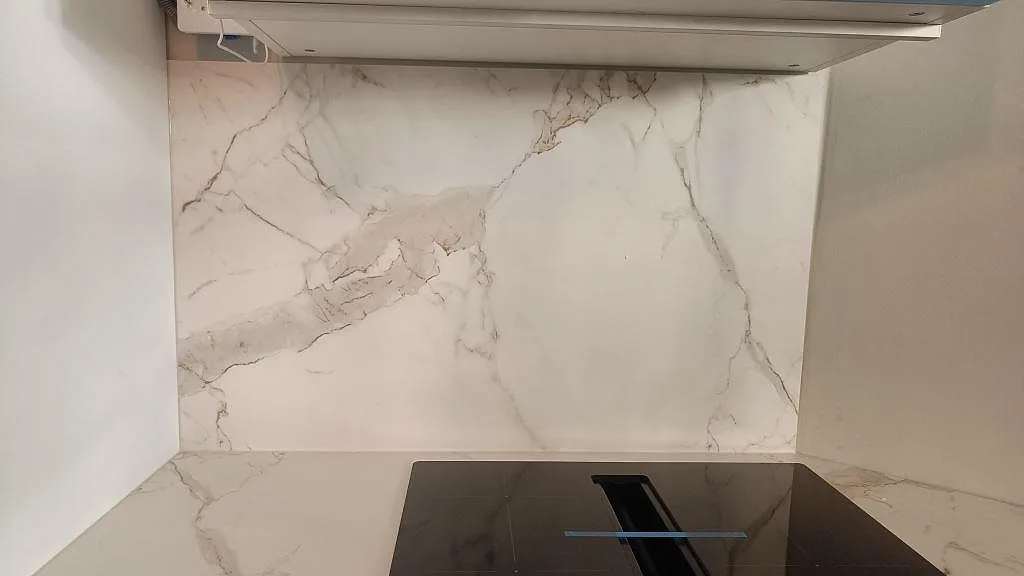 Stänkskydd och bänkskiva i matt Dekton Entzo keramik ovanför svart induktionshäll i kök i Göteborg.