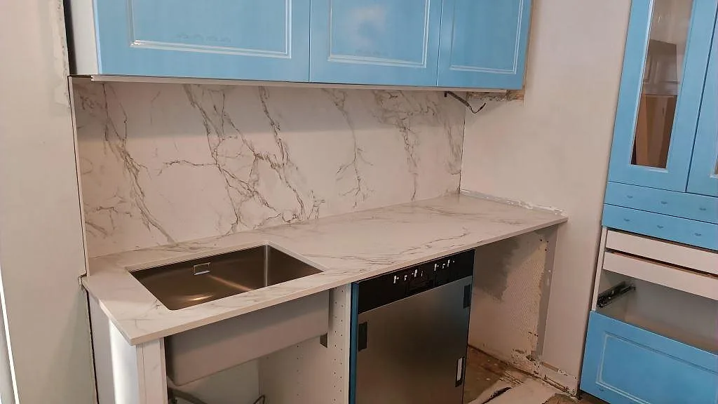 L-formad köksbänkskiva i matt Dekton Entzo keramik med underlimmad rostfri diskho och stänkskydd i ett kök i Göteborg.