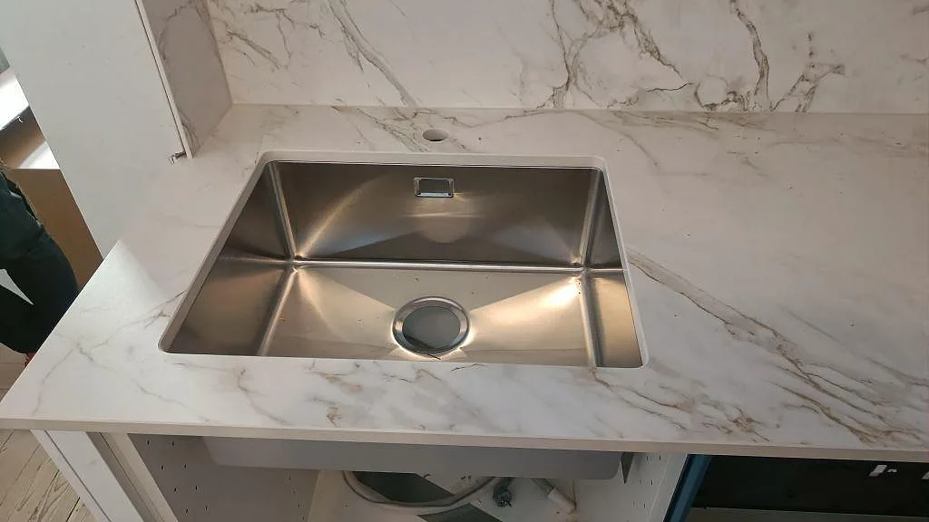 Närbild på underlimmad rostfri diskho i matt Dekton Entzo köksbänkskiva med marmorerad ådring i Göteborg.