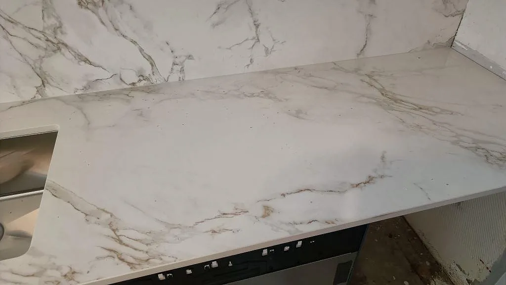 Arbetsyta i matt Dekton Entzo keramik med ljus marmorliknande ådring och stänkskydd vid diskbänken i Göteborg.