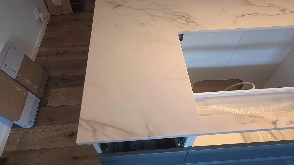 Kantdetalj på matt Dekton Entzo vid en stor öppning i kökshalvön, monterad på stommar i Häljarp.