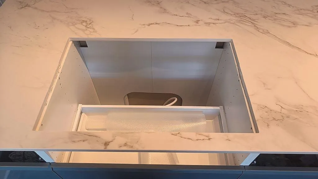 Stor urtagning i köksbänkskiva av matt Dekton Entzo med vit keramik och grå ådring i Häljarp.