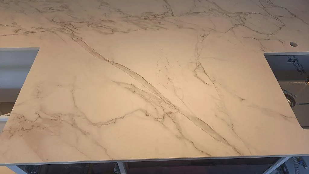 Matt Dekton Entzo som köksbänkskiva med svart diskho vid kanten och stor öppning i samma arbetsyta i Häljarp.